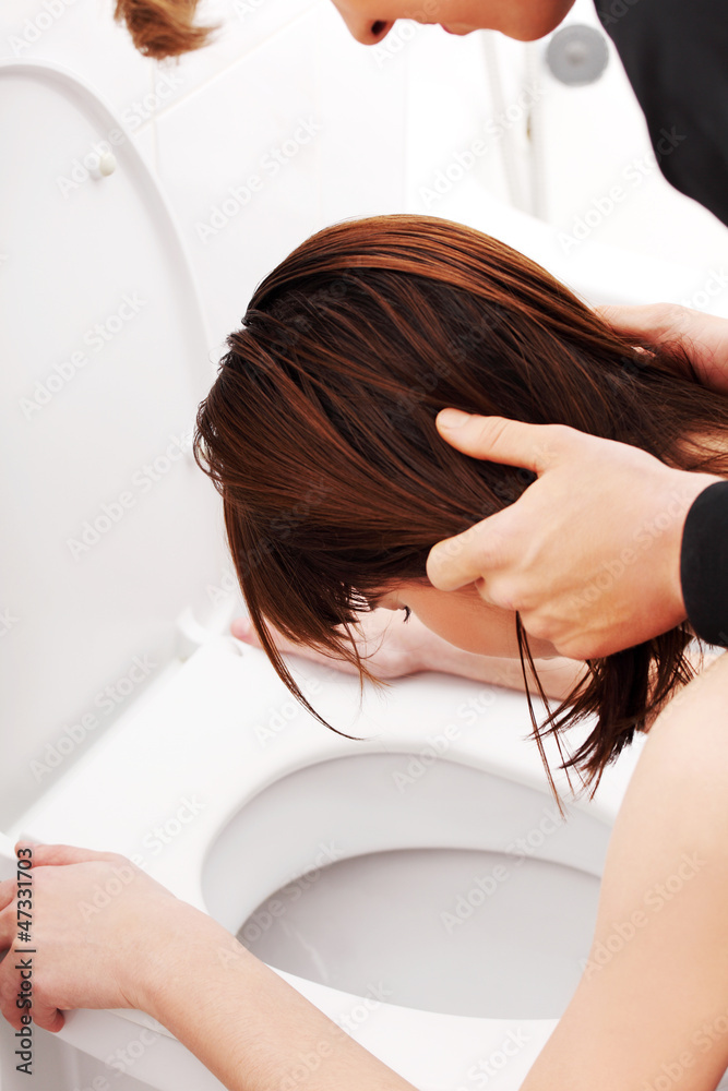 Boy holding his girlfriend head above toilet. Boy holding his girlfriend head above toilet.