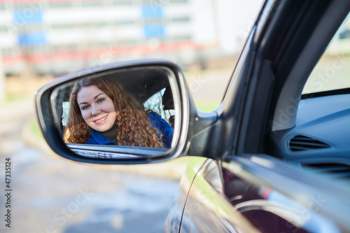 Beautiiful woman looking in car back rear-view mirror