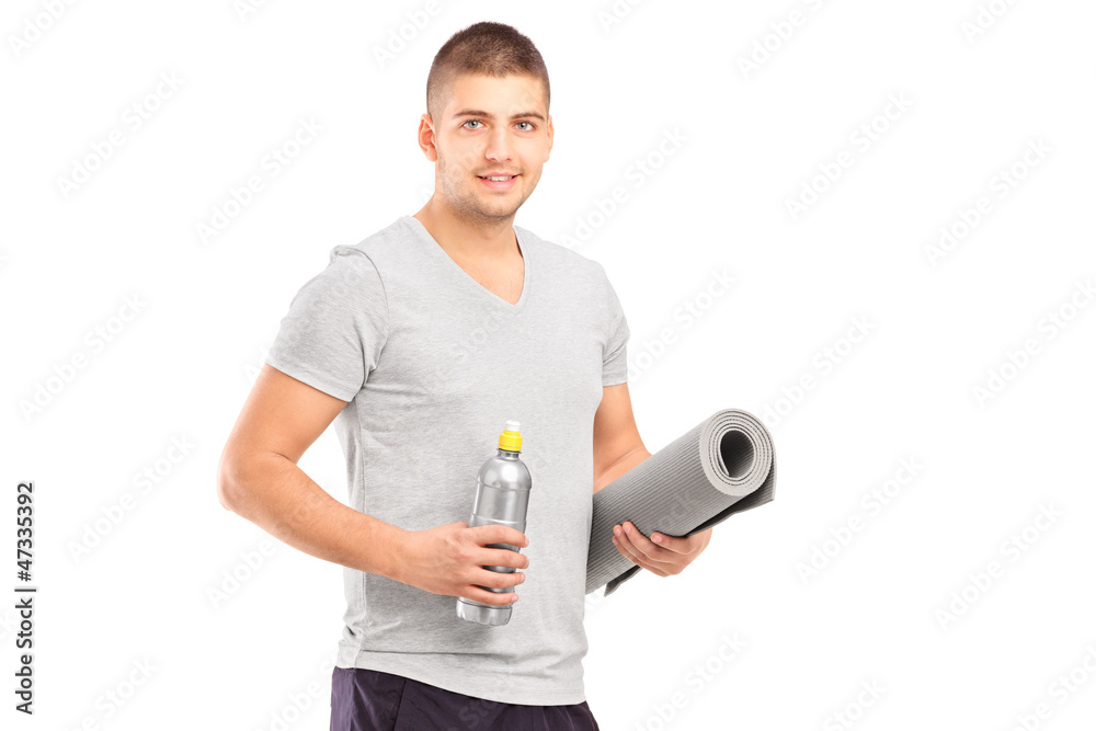 A male holding a bottle and mat after an excerise A male holding a bottle and mat after an excerise