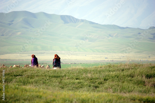Two ladies in national dress walking in the green hills of Turkmenistan near the Iranian border.