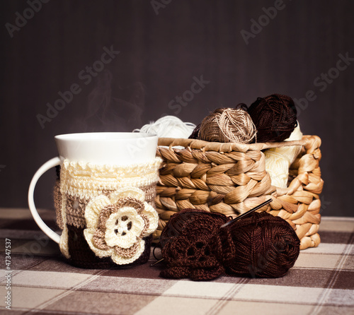 Crochet, skeins of yarn and cup of coffee on a dark background