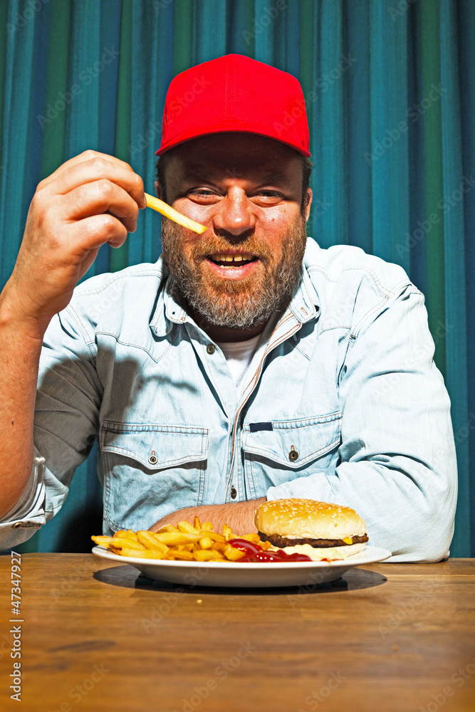 Man with beard eating fast food meal. Trucker with red cap. Man with beard eating fast food meal. Trucker with red cap.