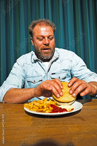 Lonely man with beard eating fast food meal.