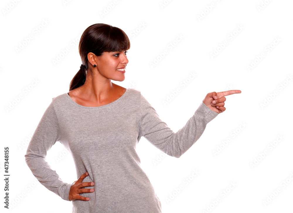 Smiling young woman on grey dress pointing left Smiling young woman on grey dress pointing left