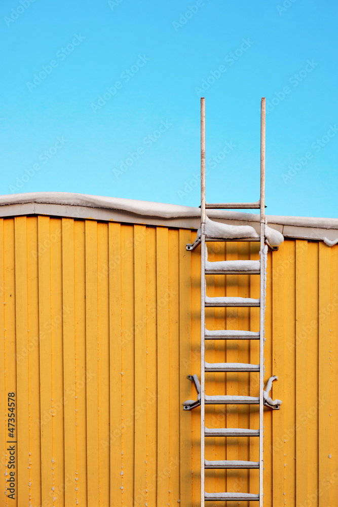 Metal ladder on yellow wall