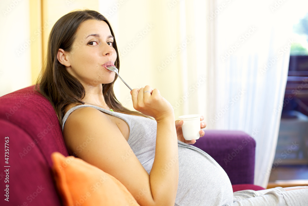 Happy pregnant woman licking spoong with yogurt Happy pregnant woman licking spoong with yogurt