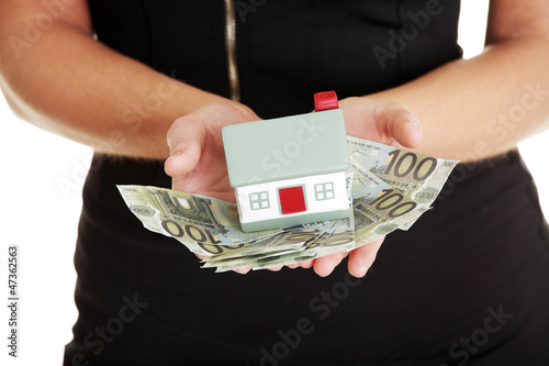 Woman holding euros bills and house model