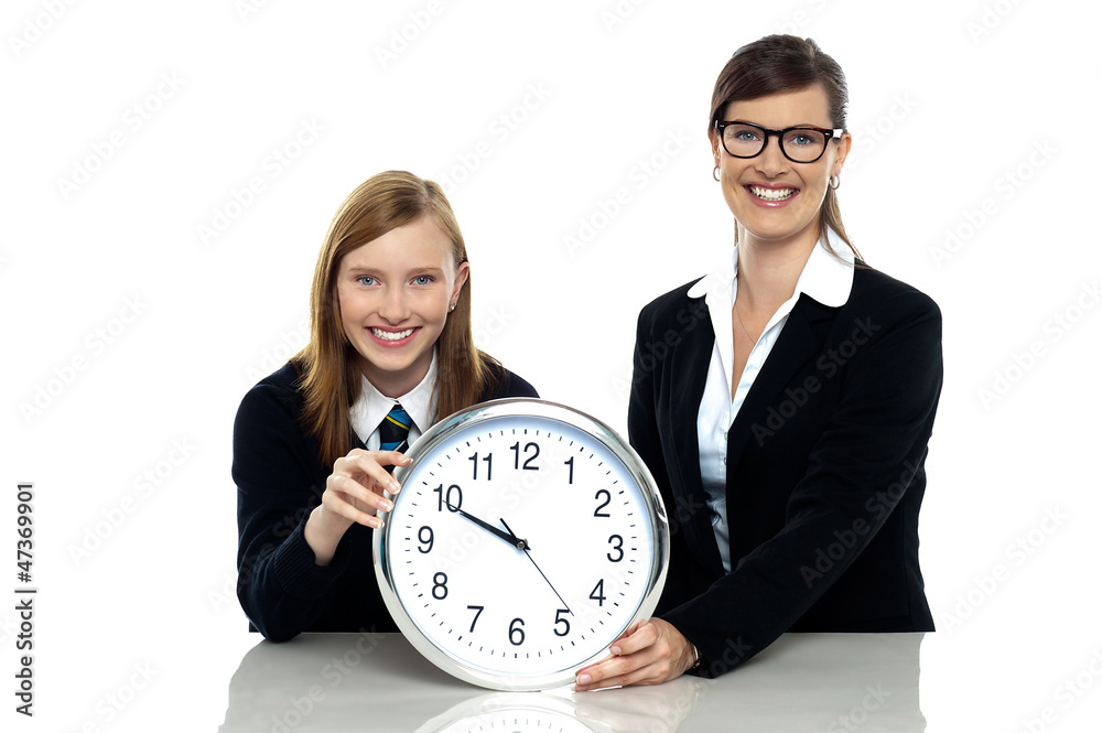 Pretty student holding clock with her teacher Pretty student holding clock with her teacher