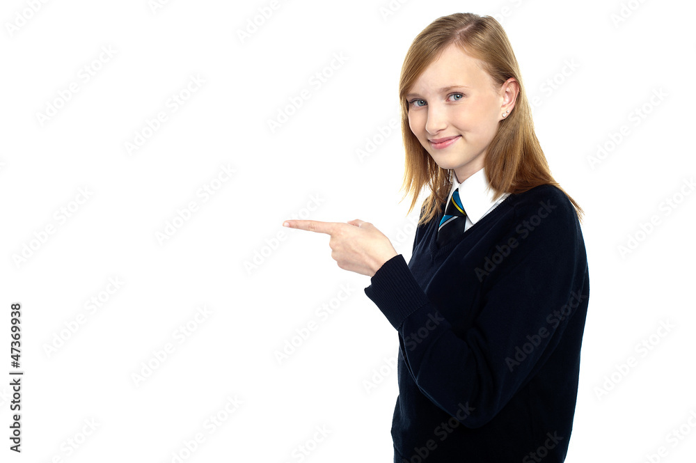 Pretty schoolgirl pointing towards copy space area Pretty schoolgirl pointing towards copy space area