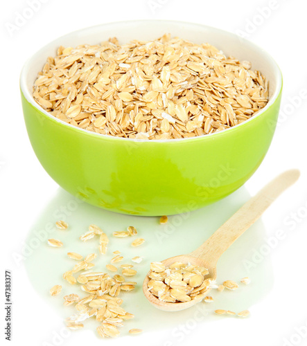 Green bowl full of oat flakes with wooden spoon isolated