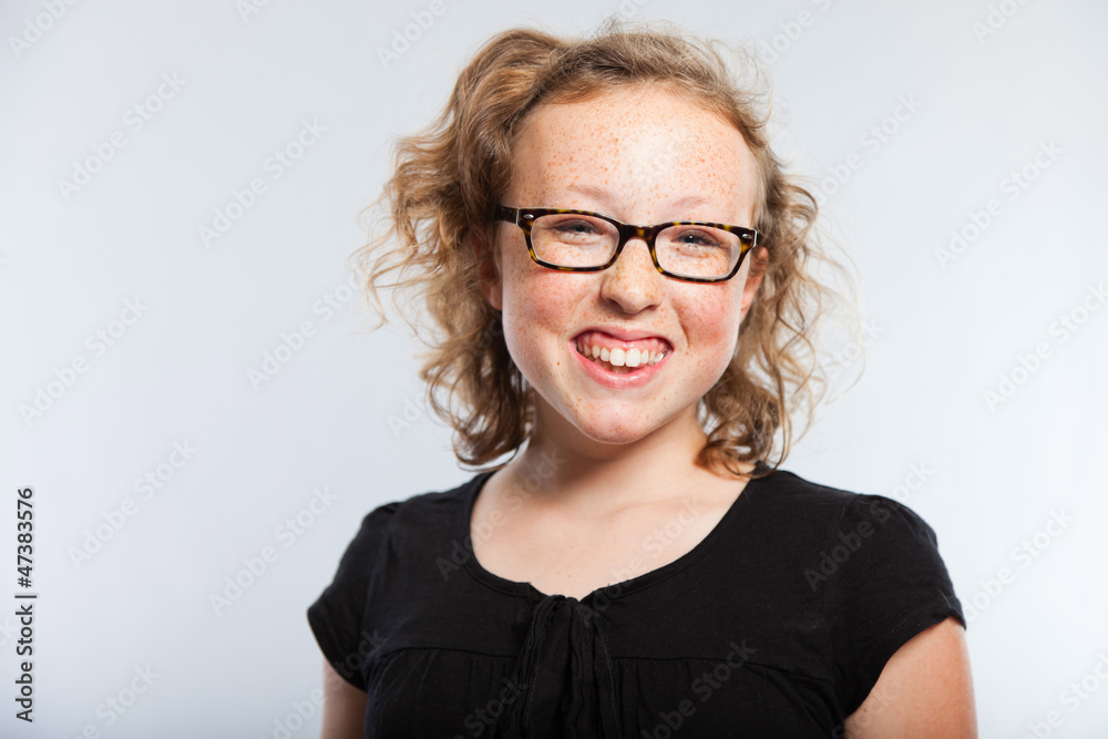 Happy funny teenage girl with curly blonde hair. Studio shot.