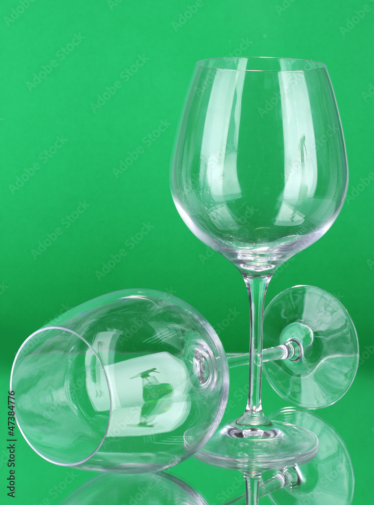 Two empty wine glasses on color background