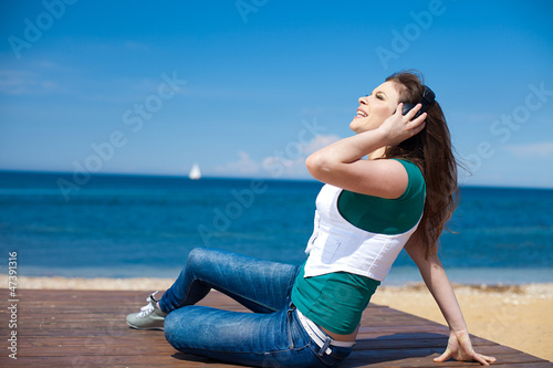 woman with headphones against the blue sky on beach