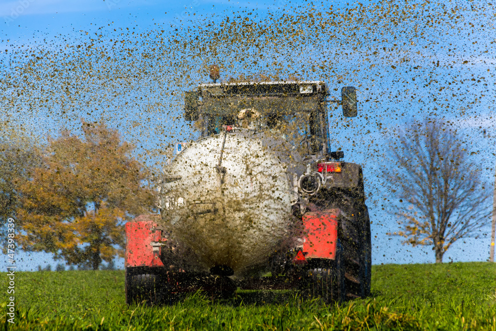 Naklejka premium Traktor düngt mit Gülle ein Feld