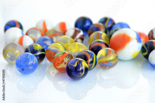 A handful of colorful glass marbles on a white background. © florinoprea