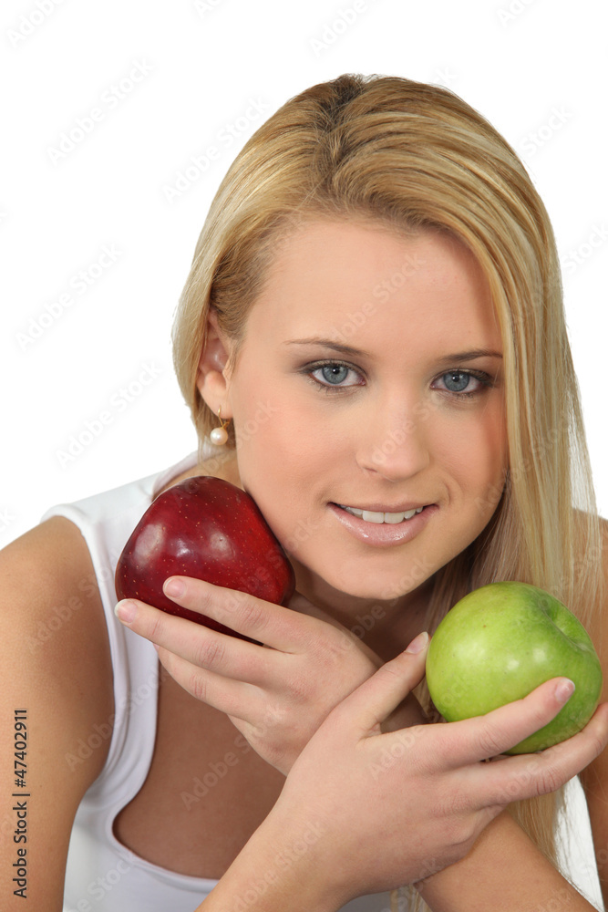 Young blonde woman with a red and a green apple Young blonde woman with a red and a green apple