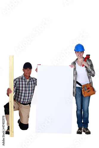 Carpenter and plumber stood with marketing board © auremar