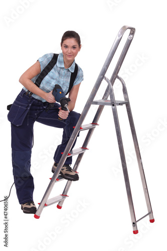female craftsman with drill and ladder