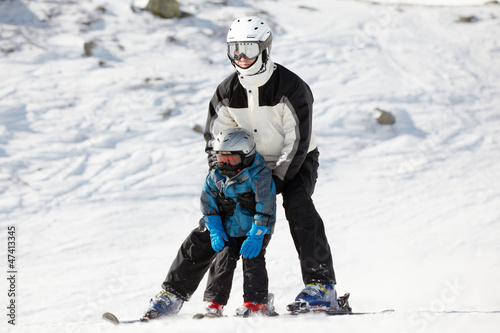 Father supports his child when they slide on alpine skis