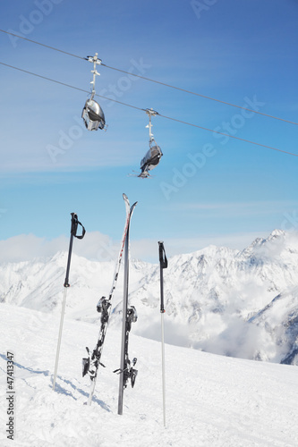 Pair of ski and poles stick out of snow against snowy mountains
