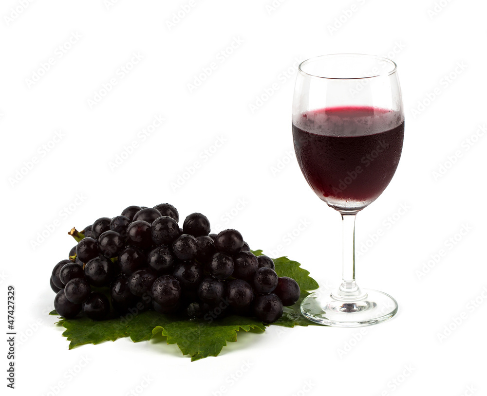 Red grape with green leaf and a glass of red wine isolated on w Red grape with green leaf and a glass of red wine isolated on w