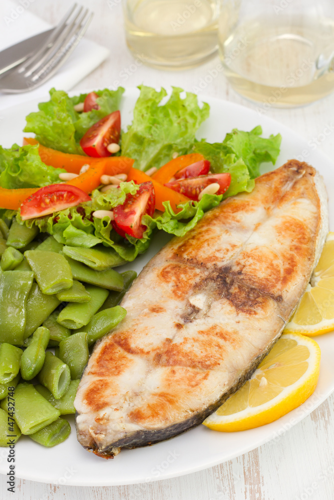 fish with vegetables on the plate and glass of wine