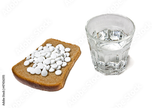 Pills, bread, glass of water on white background