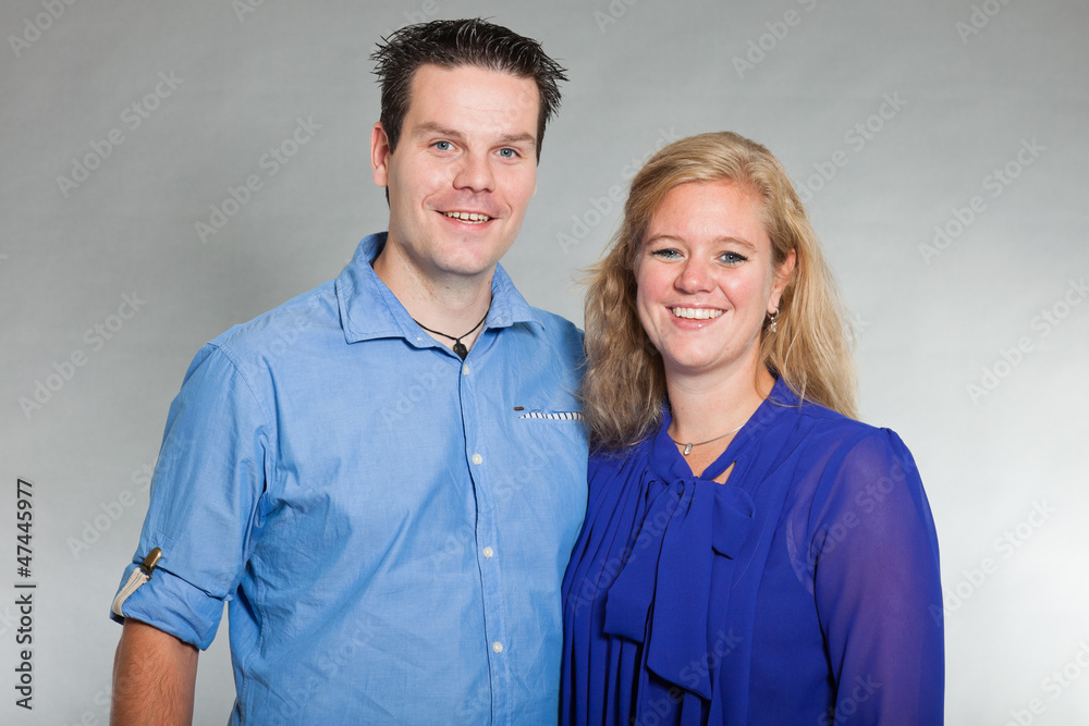 Happy young couple in love. Studio shot against grey.