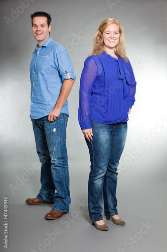 Happy young couple in love. Studio shot against grey.