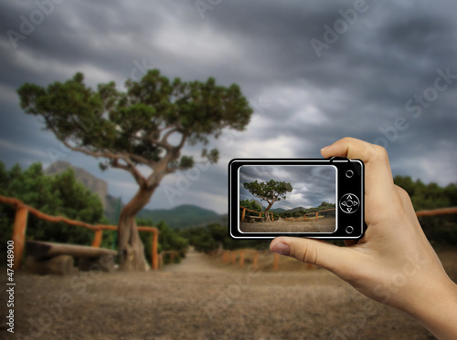 Tourist Holds Up Abstract Camera at mountain landscape