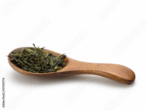 Green tea leaves and wooden scoop white background