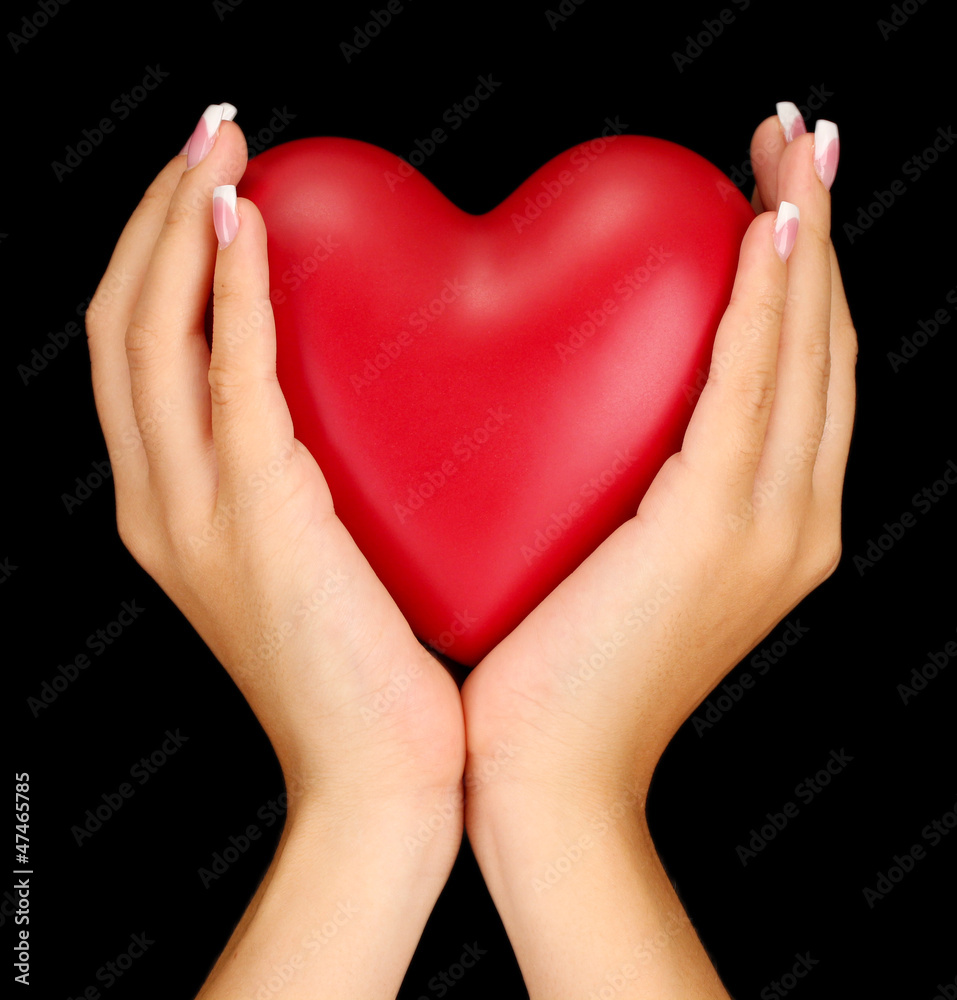 Obraz premium Red heart in woman's hands, on black background close-up