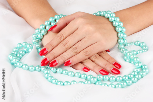 Female hands holding beads on color background