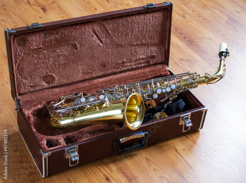 Saxophone with case on wood floor