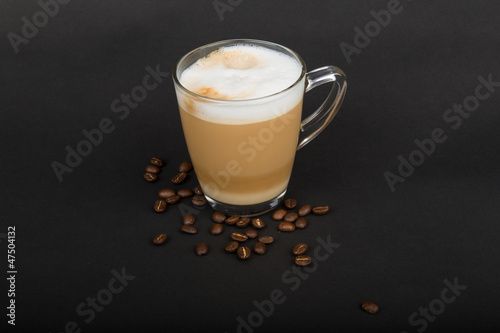 Cappuccino im Glas mit Kaffeebohnen vor schwarzem Hintergrund