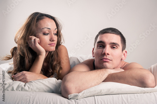 Closeup portrait of a tired young couple lying in bed.