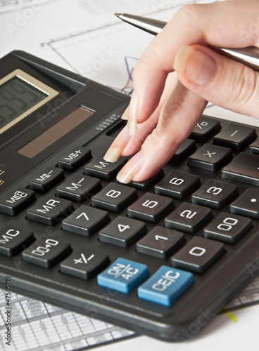 Woman's hand with a pen, calculator and the financial report 