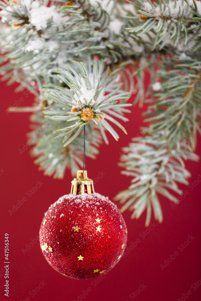 Red ball hanging on Christmas tree over red background