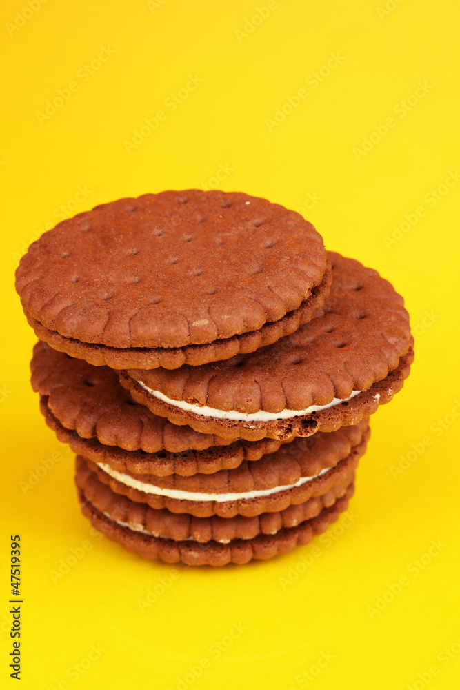 Chocolate cookies with creamy layer on yellow background Chocolate cookies with creamy layer on yellow background