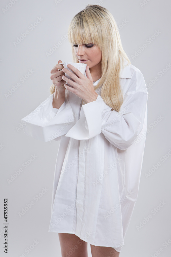 junge blonde Frau im Männerhemd trinkt Tee aus einer Tasse Stock Photo |  Adobe Stock