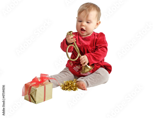 Baby girl in red velvet dress inspects toy brass horn