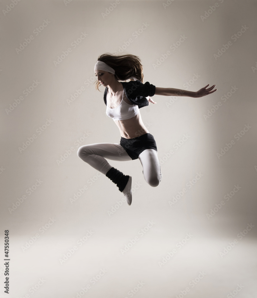A young and fit Caucasian woman jumping in sporty clothes