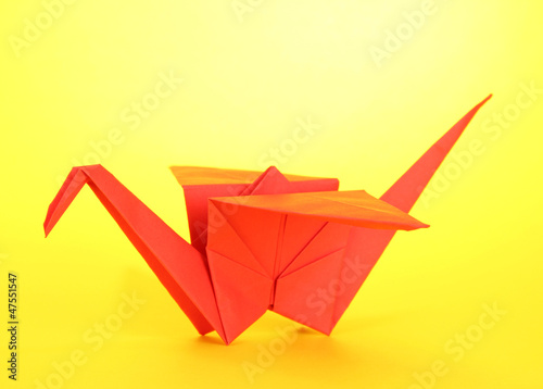 Origami crane on yellow background.