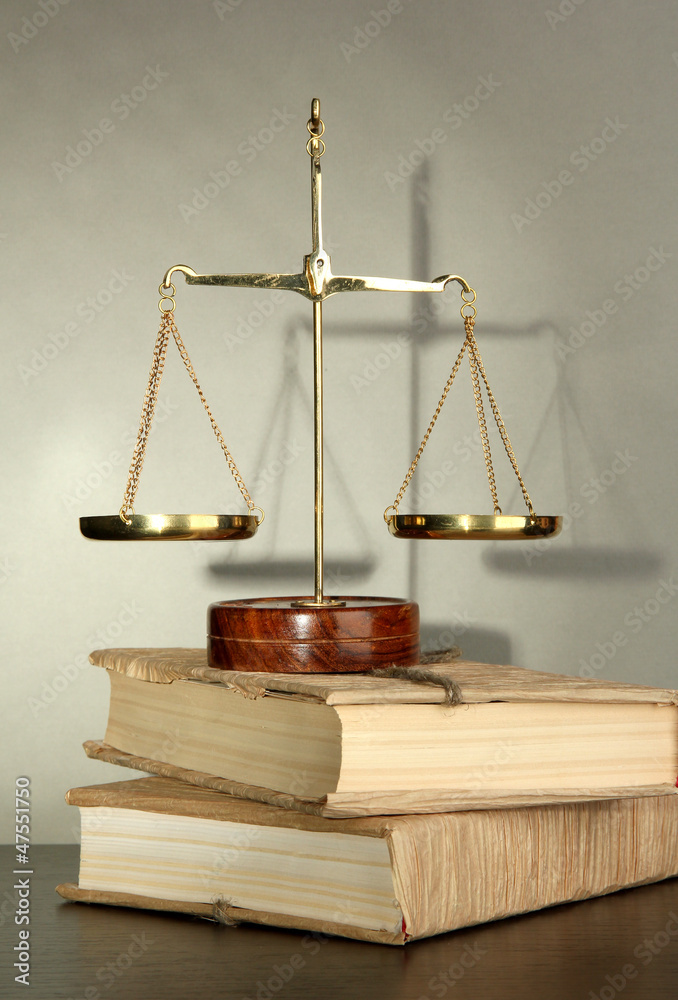 Gold scales of justice and books on grey background Gold scales of justice and books on grey background