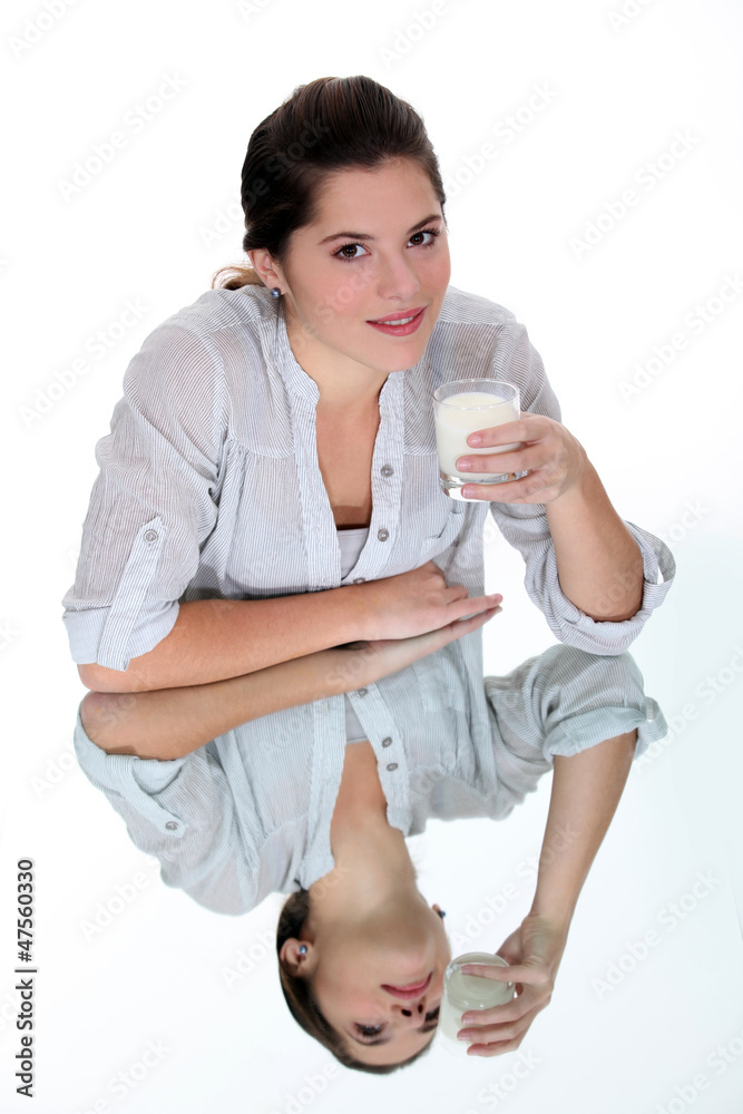 Woman drinking a glass of milk on a mirrored table Woman drinking a glass of milk on a mirrored table