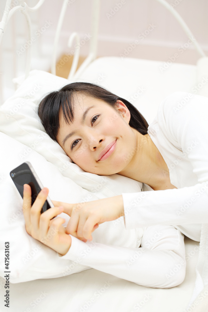 スマートフォンを寝ながら使う女の子