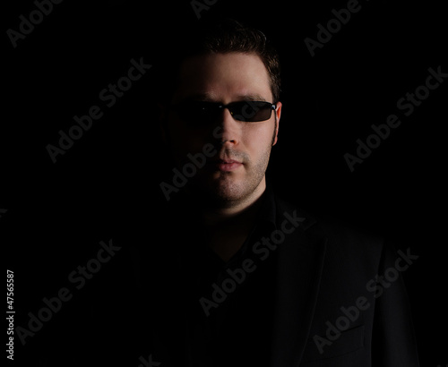 Portrait of man in black suit on black background