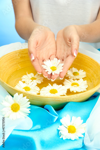 woman hands with wooden bowl of water with flowers 