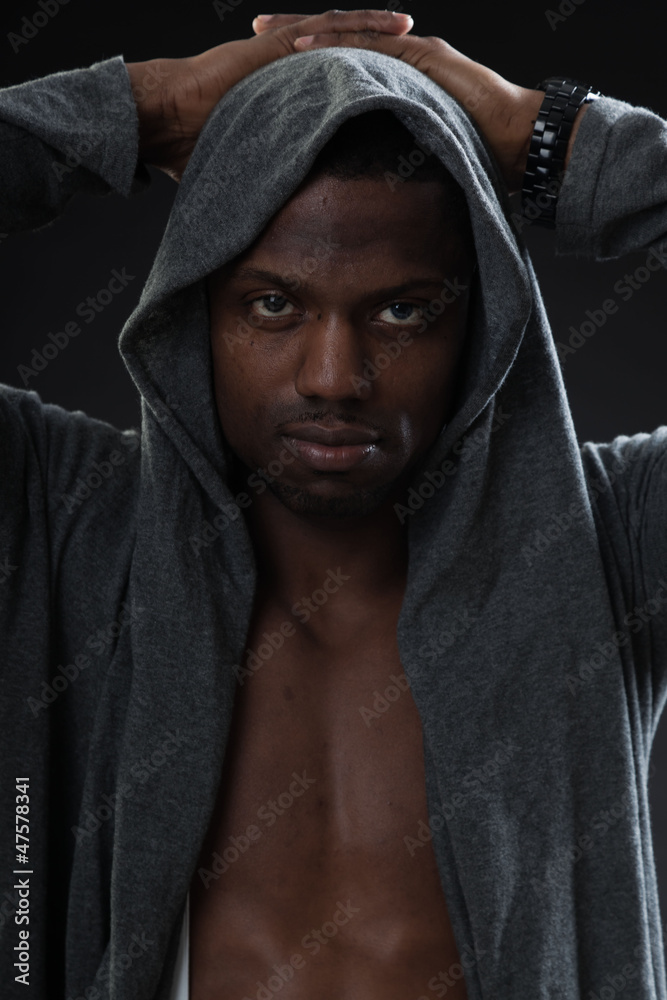 Black man urban style looking tough on dark background. Studio.