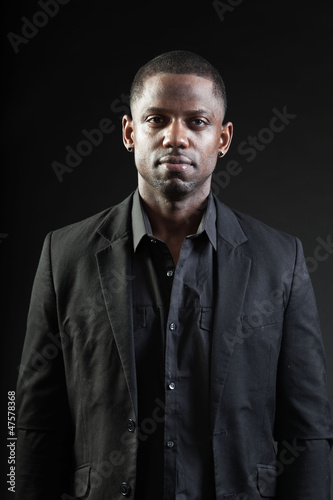 Young black man wearing suit on dark background. Studio shot
